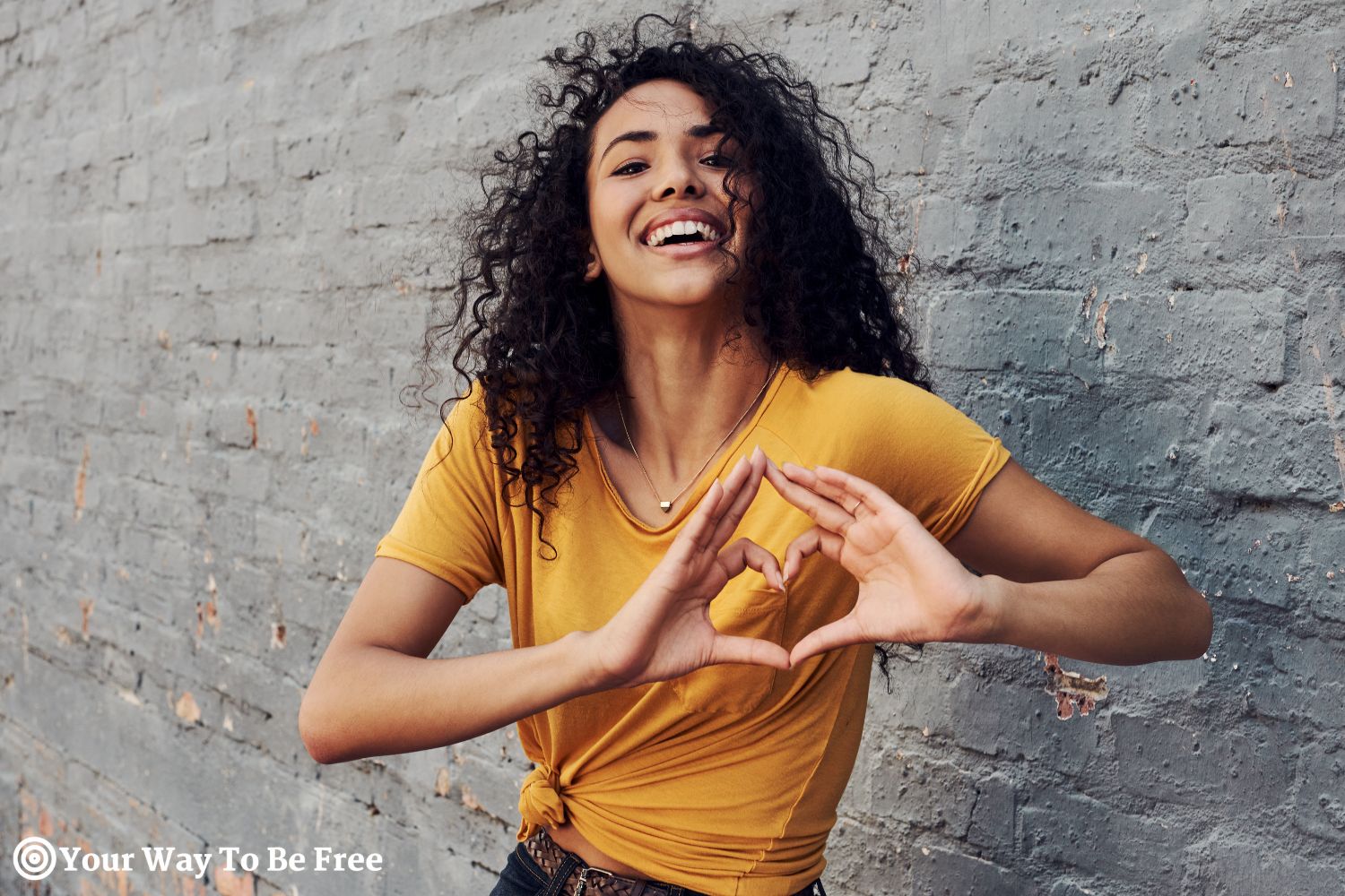 a woman making a heart shape with her hands. she shows acts of kindness